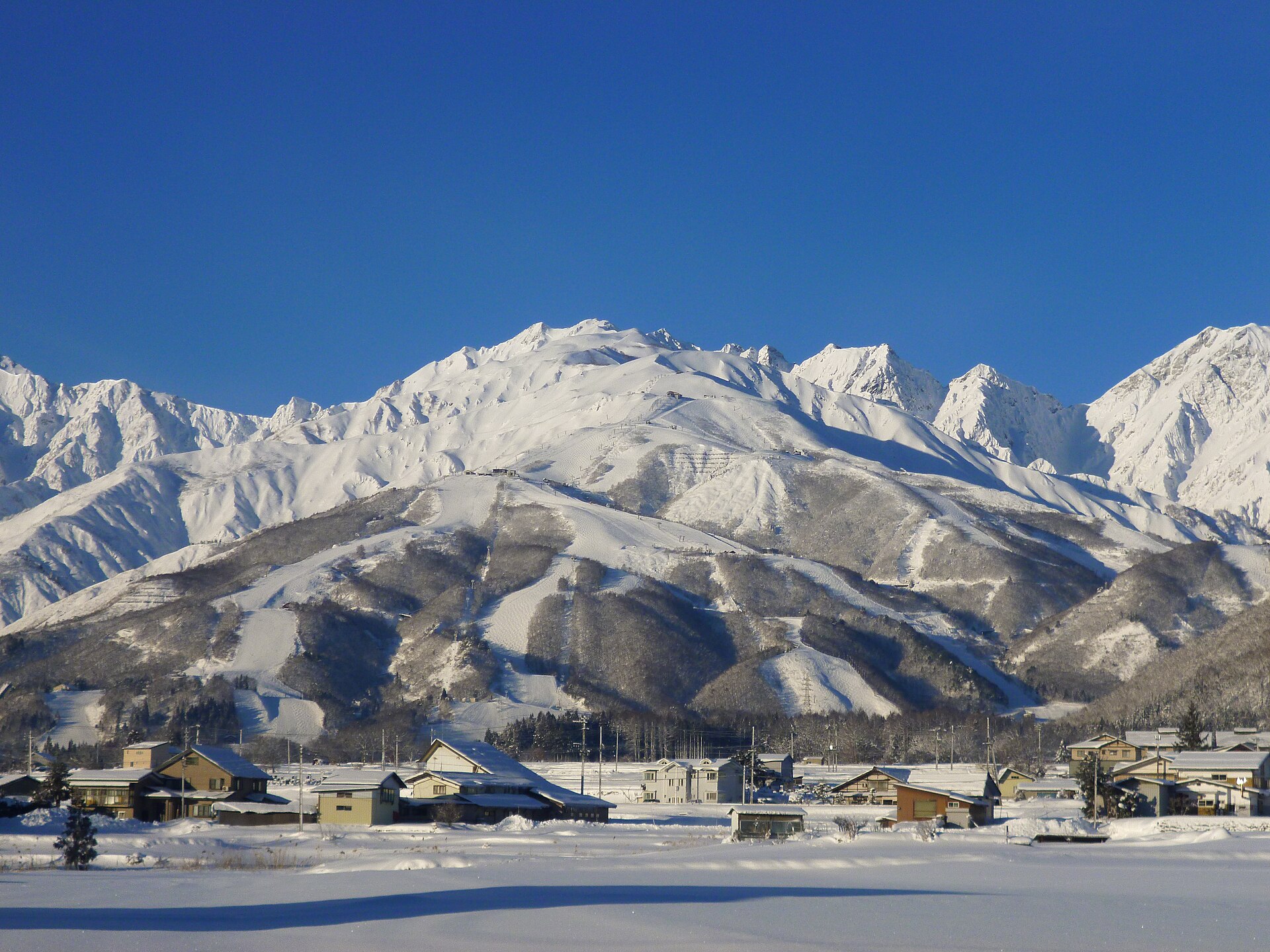 雪に覆われた冬の八方尾根と白馬村の集落