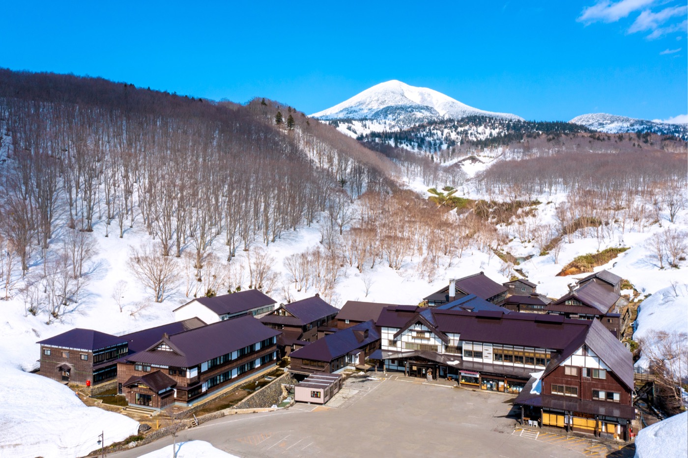 雪の残る八甲田の山ふところに建つ酸ヶ湯温泉旅館の全景